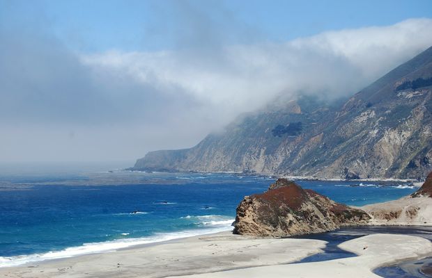 The Pacific breaking on a rocky shore below coastal hills