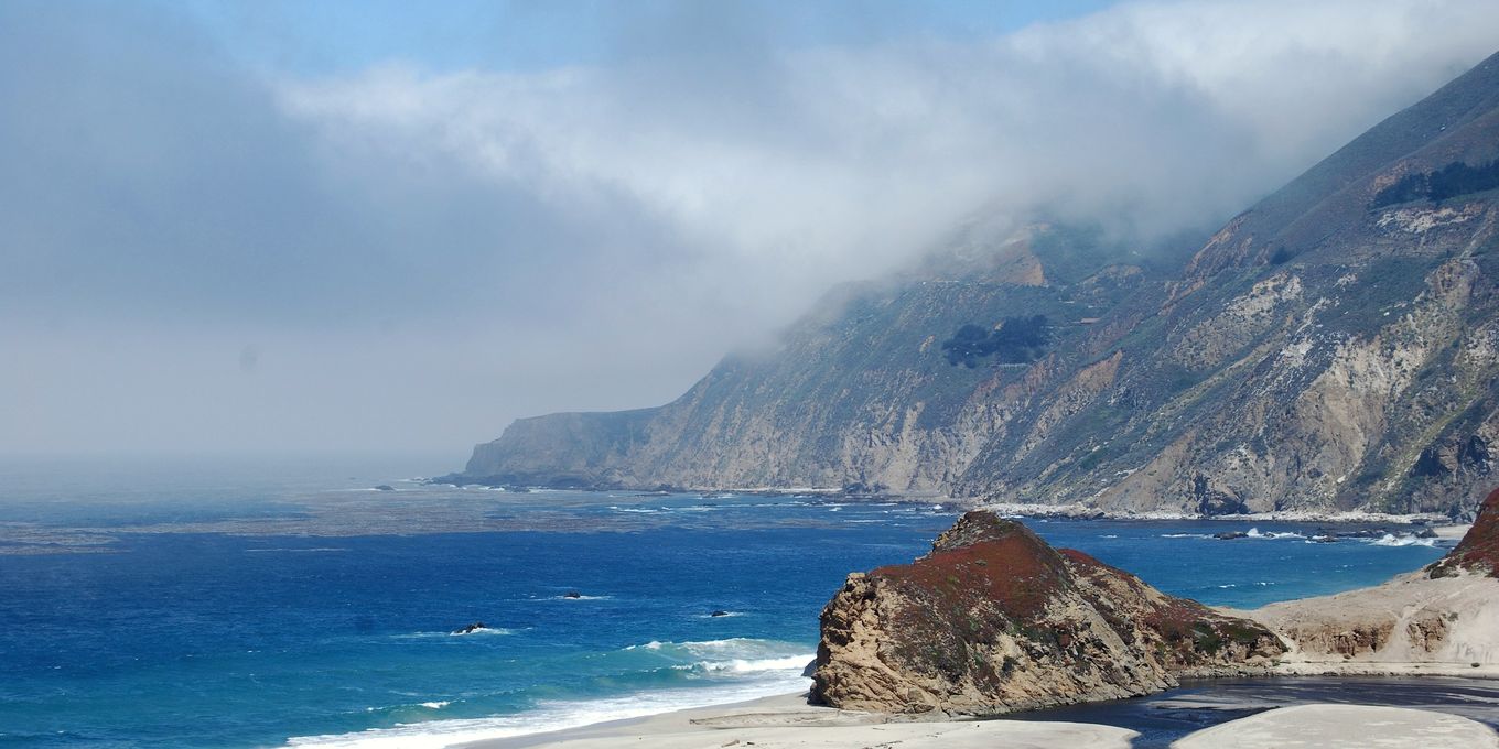 The Pacific breaking on a rocky shore below coastal hills