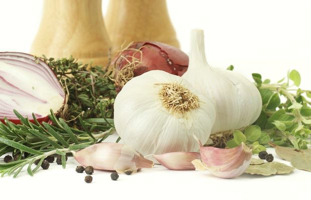 A red onion, garlic bulbs and herbs