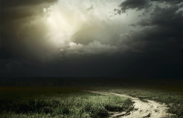 Dark storm clouds over a dirt track and grass