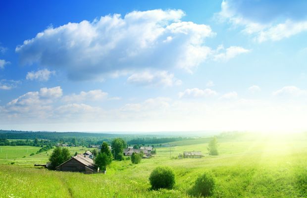 Green meadow and a farmhouse under clearing cloud
