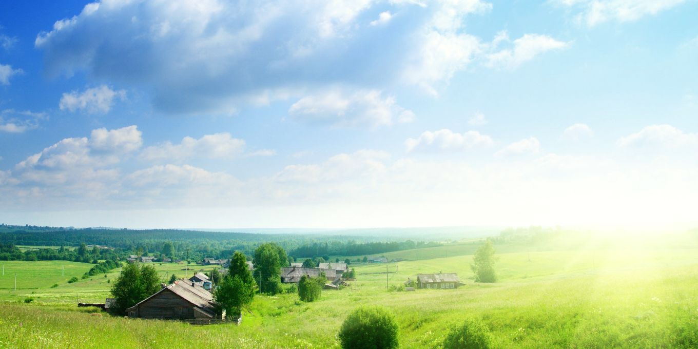 Green meadow and a farmhouse under clearing cloud