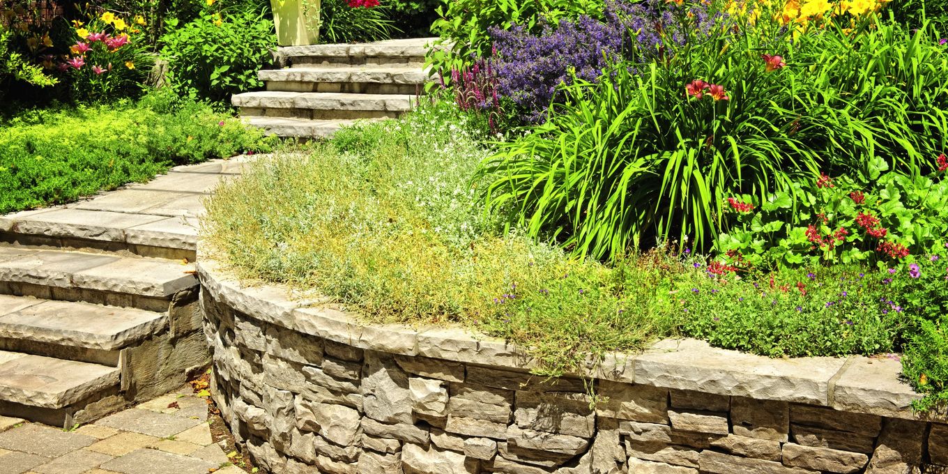 Stone steps and a curved retaining wall around a planted bed