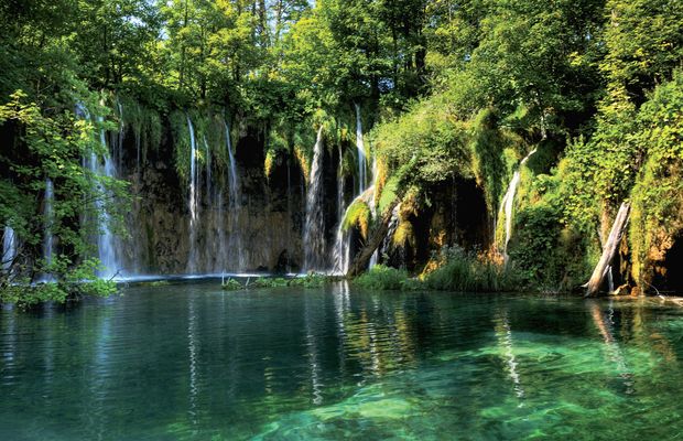 Waterfalls spilling into a clear green lake