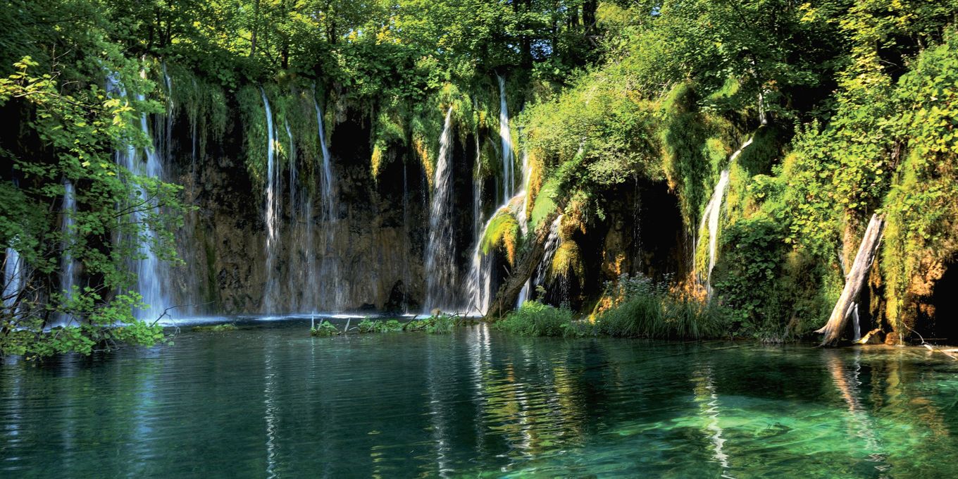 Waterfalls spilling into a clear green lake